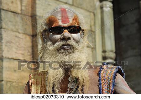 Holy man, Sadhu, with a painted face, a long beard and sunglasses, Pandra Shivalaya Complex, Pashupatinath on the sacred Bagmati River, Kathmandu, Nepal, Asia View Large Photo Image Stock Image - Holy man, Sadhu, with a painted face, a long beard and sunglasses, Pandra Shivalaya Complex, Pashupatinath on the sacred Bagmati River, Kathmandu, Nepal, Asia. Fotosearch