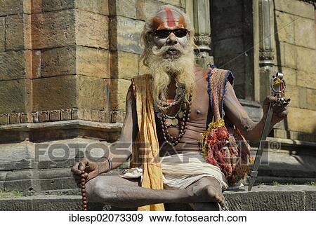 Holy man, Sadhu, with a painted face, a long beard and sunglasses, Pandra Shivalaya Complex, Pashupatinath on the sacred Bagmati River, Kathmandu, Nepal, Asia View Large Photo Image Stock Photo - Holy man, Sadhu, with a painted face, a long beard and sunglasses, Pandra Shivalaya Complex, Pashupatinath on the sacred Bagmati River, Kathmandu, Nepal, Asia. Fotosearch