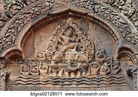 Stock Image - Indra, god of the sky, riding a chariot drawn by a three-headed elephant, part of the bas-reliefs of the east-facing pediment of the Northern Library, Banteay Srei temple, Citadel of the Women, Angkor, Cambodia, Southeast Asia, Asia. Fotosearch