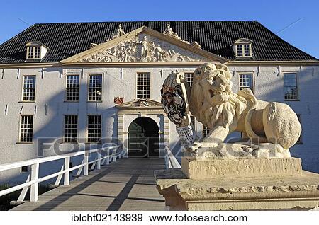 Stock Photo - Lion sculpture and Norderburg Moated Castle, now a secondary school, Dornum, East Frisia, Lower Saxony, Germany, Europe. Fotosearch