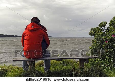 Lonely man sitting on the banks of the Groensund sound, Denmark, Europe View Large Photo Image Stock Photograph - Lonely man sitting on the banks of the Groensund sound, Denmark, Europe. Fotosearch