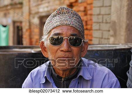Stock Image - Man wearing sunglasses and traditional headwear, portrait, Bhaktapur, Kathmandu Valley, Nepal, Asia. Fotosearch