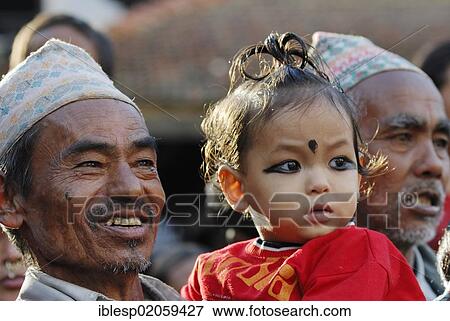 Stock Photo - Men with traditional headwear and child watching procession, Taumadhi square, Bhaktapur, Kathmandu Valley, Nepal, Asia. Fotosearch