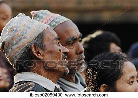 Stock Image - Men with traditional headwear watching procession, Taumadhi square, Bhaktapur, Kathmandu Valley, Nepal, Asia. Fotosearch