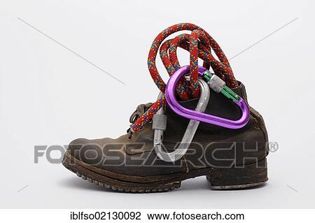 Stock Image - Old mountain boots with nailed soles and iron heels, with a climbing rope and carabiner. Fotosearch