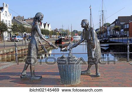 Old Port with the bronze sculpture Toerfwieven, depicting two female peat workers in Weener, East Frisia, Lower Saxony, Germany, Europe View Large Photo Image Stock Photo - Old Port with the bronze sculpture Toerfwieven, depicting two female peat workers in Weener, East Frisia, Lower Saxony, Germany, Europe. Fotosearch