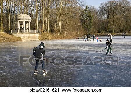 Stock Image - People on the frozen lake in "Stadtwald" park, Krefeld, North Rhine-Westphalia, Germany, Europe. Fotosearch