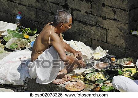 Stock Photograph - Pilgrim on the steps of the Pandra Shivalaya Complex opposite the ghats of Pashupatinath on the sacred Bagmati River, Kathmandu, Nepal, Asia. Fotosearch