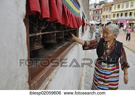 Stock Photograph - Pilgrim walking around stupa of Boudhanath and turning prayer wheel, Kathmandu, Nepal, Asia. Fotosearch