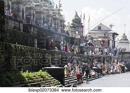 Picture - Pilgrims on the steps of the Pandra Shivalaya Complex opposite the Ghats of Pashupatinath on the holy Bagmati River, Kathmandu, Nepal, Asia. Fotosearch