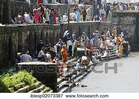 Stock Photo - Pilgrims on the steps of the Pandra Shivalaya complex opposite the ghats of Pashupatinath on the holy Bagmati River, Kathmandu, Nepal, Asia. Fotosearch