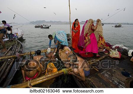 Stock Photograph - Pilgrims taking their holy dip in the water at Sangam, the confluence of the holy rivers Ganges, Yamuna and Saraswati, in Allahabad, Uttar Pradesh, India, Asia. Fotosearch