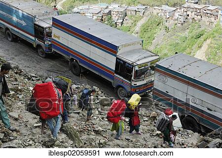 Stock Image - Porters carrying the luggage of tourists, border town Nyalam - Zhangmu on the Friendship Highway Tibet - Nepal, Himalayas, Tibet, China, Asia. Fotosearch