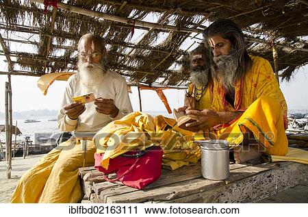 Stock Image - Sadhus reciting from the holy books in the morning, at Sangam, the confluence of the holy rivers Ganges, Yamuna and Saraswati, in Allahabad, Uttar Pradesh, India, Asia. Fotosearch