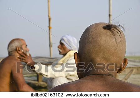 Stock Image - Shaving the head as part of a religious ritual, performed at Sangam, the confluence of the holy rivers Ganges, Yamuna and Saraswati, in Allahabad, Uttar Pradesh, India, Asia. Fotosearch