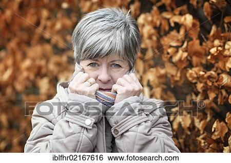 Shivering woman pulling up the collar of her coat View Large Photo Image Stock Photograph - Shivering woman pulling up the collar of her coat. Fotosearch