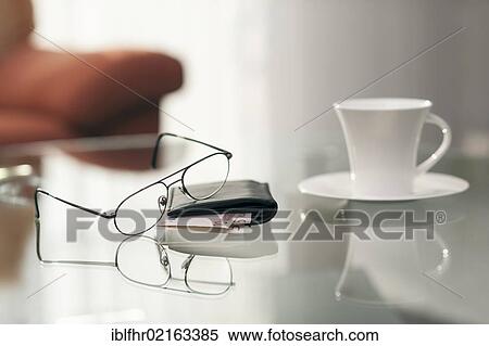 Still life with a pair of glasses, a wallet and a coffee cup on a glass table View Large Photo Image Stock Photography - Still life with a pair of glasses, a wallet and a coffee cup on a glass table. Fotosearch