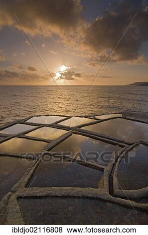 Sunrise and clouds above the typical salt pans or salterns, Qbajjar, near Marsalforn, northern coast of Gozo, Malta, Europe View Large Photo Image Stock Photo - Sunrise and clouds above the typical salt pans or salterns, Qbajjar, near Marsalforn, northern coast of Gozo, Malta, Europe. Fotosearch