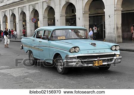 Stock Image - Taxi, vintage Ford car from the 50s in the centre of Havana, Centro Habana, Cuba, Greater Antilles, Caribbean, Central America, America, North America. Fotosearch