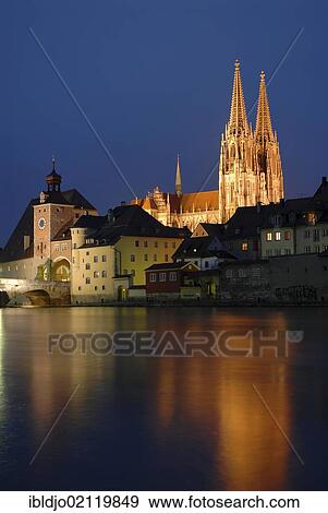Stock Photo - The floodlit towers of the cathedral as seen across the Danube river, at dusk, Regensburg, Upper Palatinate, Bavaria, Germany, Europe. Fotosearch
