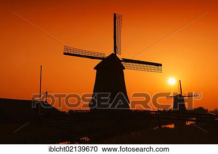 Stock Image - Windmills at Sunset, Schermerhorn, Schermer, North Holland, Holland, Netherlands, Europe. Fotosearch