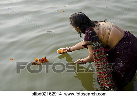 Woman giving offerings to the holy river Ganges as part of her pilgrimage to Varanasi, Uttar Pradesh, India, Asia View Large Photo Image Picture - Woman giving offerings to the holy river Ganges as part of her pilgrimage to Varanasi, Uttar Pradesh, India, Asia. Fotosearch