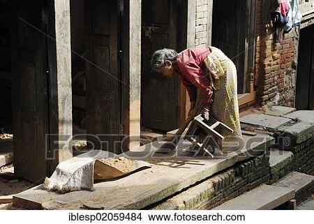 Picture - Woman in traditional dress sweeping the floor, Bhaktapur, Kathmandu Valley, Nepal, Asia. Fotosearch