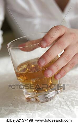 Stock Photo - Woman's hand holding a glass of hard liquor, female alcoholism. Fotosearch