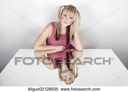 Stock Photography - Young blond woman with red painted cheeks, smiling, with a mirrored image. Fotosearch