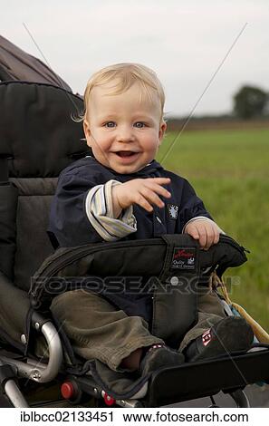 Stock Image - Young boy, 1, in a stroller, looking happy, Germany, Europe. Fotosearch