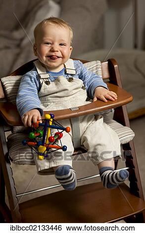 Young boy, 8 months, wearing overalls with toys in a highchair, sticking out his tongue, Germany, Europe View Large Photo Image Stock Photograph - Young boy, 8 months, wearing overalls with toys in a highchair, sticking out his tongue, Germany, Europe. Fotosearch