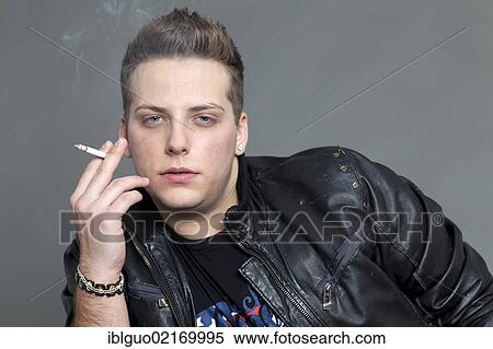 Stock Photography - Young man in a leather jacket smoking a cigarette, portrait. Fotosearch