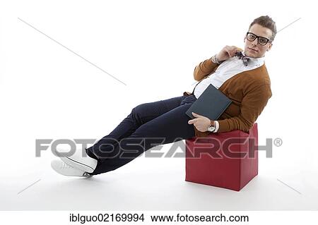 Young man with glasses and a bow tie sitting on a cube View Large Photo Image Picture - Young man with glasses and a bow tie sitting on a cube. Fotosearch