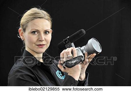 Stock Photography - Young professional videographer shooting with a film camera. Fotosearch