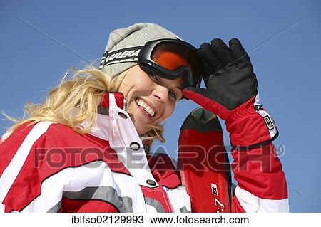 Young woman, about 25, wearing a red-white ski suit and a pale gray cap against a clear blue sky, smiling, with one hand on her goggles, Thuringian Forest, Thuringia, Germany, Europe View Large Photo Image Stock Image - Young woman, about 25, wearing a red-white ski suit and a pale gray cap against a clear blue sky, smiling, with one hand on her goggles, Thuringian Forest, Thuringia, Germany, Europe. Fotosearch