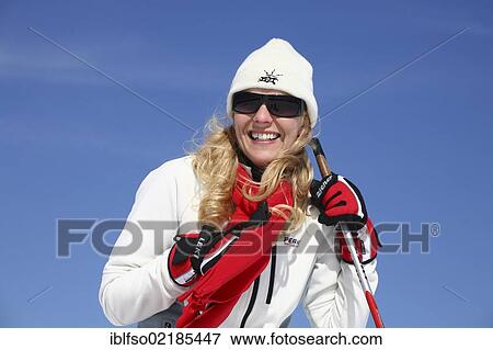 Young woman, about 25 years, wearing a bright jacket, a cap, dark sunglasses and a red scarf, against a blue sky, holding a ski stick, smiling, Thuringian Forest mountains, Thuringia, Germany, Europe View Large Photo Image Stock Photo - Young woman, about 25 years, wearing a bright jacket, a cap, dark sunglasses and a red scarf, against a blue sky, holding a ski stick, smiling, Thuringian Forest mountains, Thuringia, Germany, Europe. Fotosearch