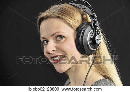 Stock Photo - Young woman listening to music with headphones. Fotosearch