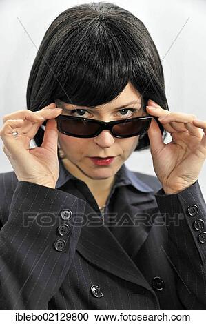 Stock Image - Young woman trying on sunglasses. Fotosearch