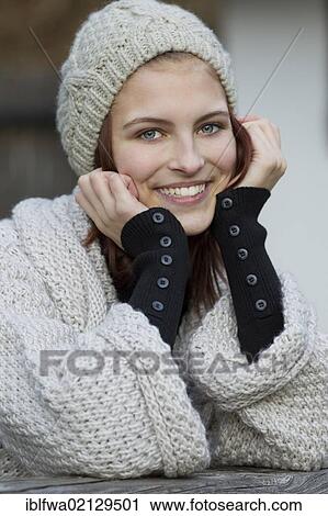Stock Image - Young woman wearing a cardigan and a woolen hat. Fotosearch