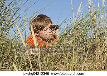 Boy in the dune grasses, looking through a telescope, Warnemunde, Mecklenburg-Western Pomerania, Germany, Europe View Large Photo Image Stock Photograph - Boy in the dune grasses, looking through a telescope, Warnemunde, Mecklenburg-Western Pomerania, Germany, Europe. Fotosearch