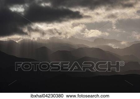 Low clouds, storm clouds with sun rays penetrating, mountainous landscape, dramatic lighting and cloudy atmosphere in Aguimes, Gran Canaria, Canary Islands, Spain, Europe View Large Photo Image Stock Image - Low clouds, storm clouds with sun rays penetrating, mountainous landscape, dramatic lighting and cloudy atmosphere in Aguimes, Gran Canaria, Canary Islands, Spain, Europe. Fotosearch