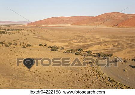 Shadow of the hot-air balloon over an arid plain and the dry riverbed of the Tsauchab river at the edge of the Namib Desert, photographed from the basket of the balloon, Namib-Naukluft National Park, Namibia, Africa View Large Photo Image Stock Photo - Shadow of the hot-air balloon over an arid plain and the dry riverbed of the Tsauchab river at the edge of the Namib Desert, photographed from the basket of the balloon, Namib-Naukluft National Park, Namibia, Africa. Fotosearch