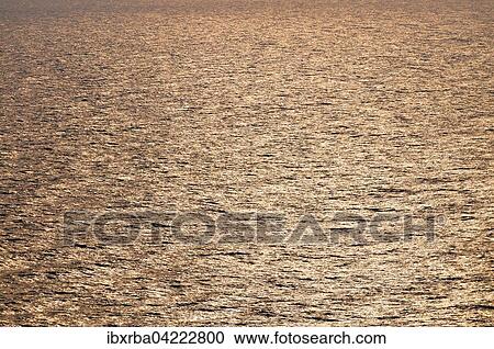 Stock Image - Water surface shimmering in the golden sunlight, Baltic Sea, island of Usedom, Mecklenburg-Western Pomerania, Germany, Europe. Fotosearch