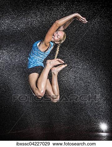 Stock Photo - Young woman, 18 years old, jumping in mist, rain. Fotosearch