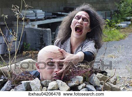 Stock Photo - Zombie grabbing the head of a man, filming, scene from a zombie comedy, short film Brain Freeze. Fotosearch
