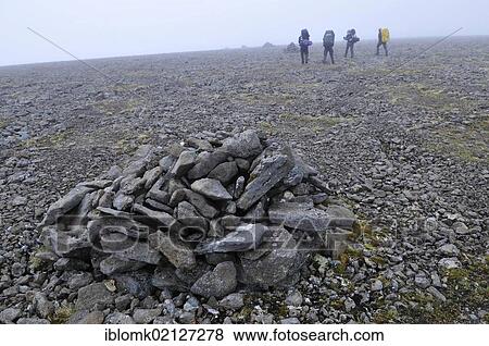 Stock Photo - A group of hikers, Varda, also known as guard, a cairn as a trail marker, Hornstrandir, Westfjords, Iceland, Europe. Fotosearch