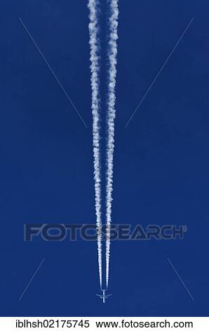 Stock Photography - Aircraft with two contrails against a blue sky. Fotosearch
