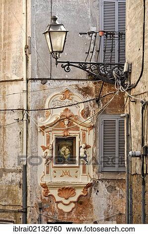 Stock Image - Angle, narrow alleyway with image of the Madonna in the mountain town of Genazzano, Lazio, Italy, Europe. Fotosearch