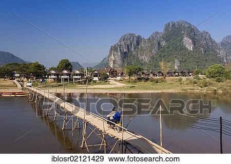 Bamboo bridge with moped rider over the Nam Song River, karst mountains, Vang Vieng, Vientiane, Laos, Indochina, Asia View Large Photo Image Stock Photo - Bamboo bridge with moped rider over the Nam Song River, karst mountains, Vang Vieng, Vientiane, Laos, Indochina, Asia. Fotosearch