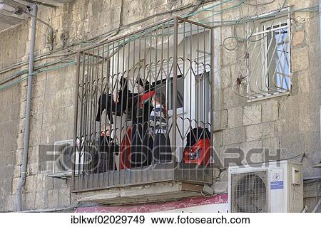 Stock Photo - Barred balcony with woman and children and air-conditioning, Me'a She'arim district, Jerusalem, Israel, Middle East, Asia. Fotosearch